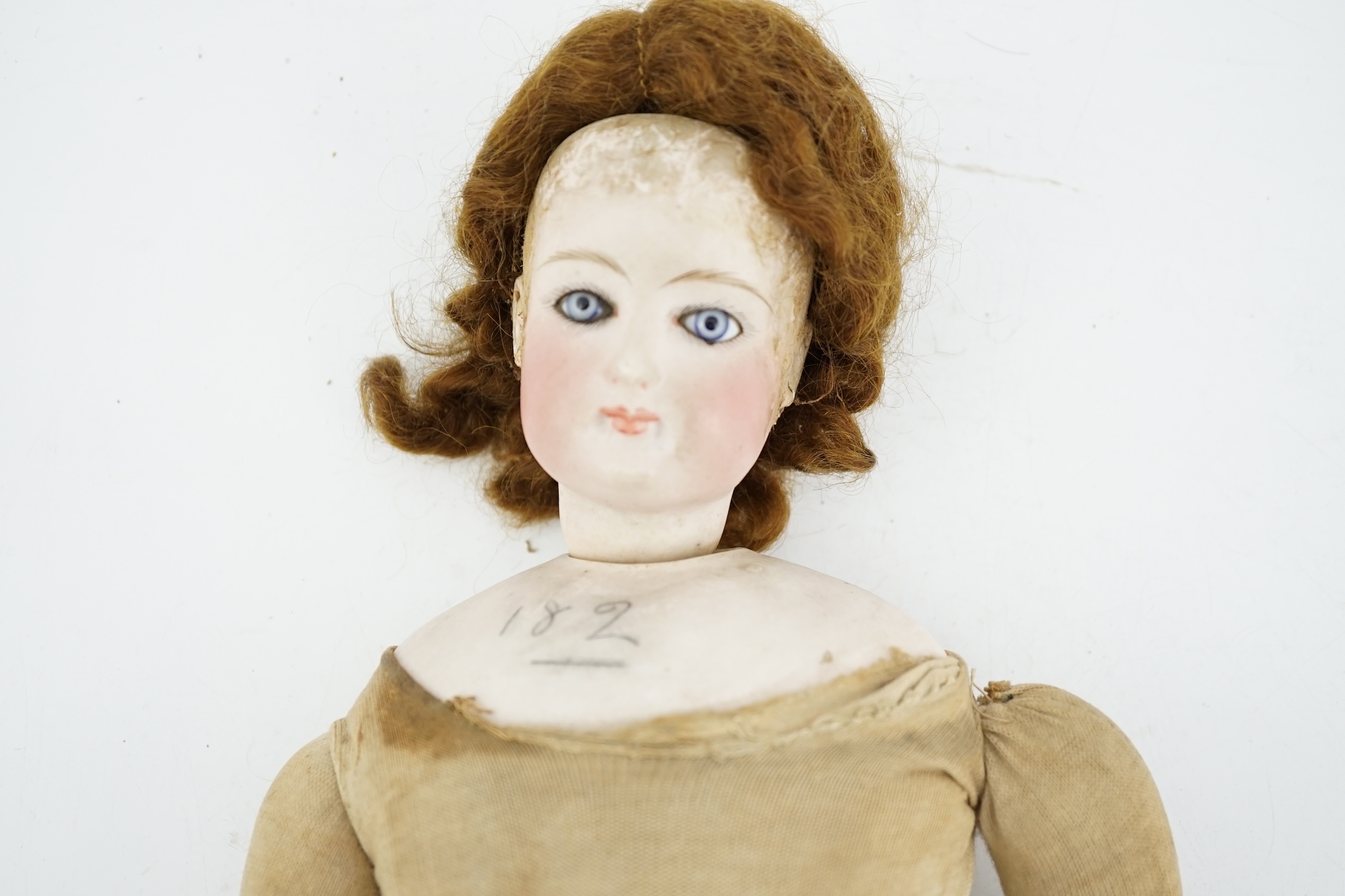 A late 19th century French biscuit head doll, possibly Simon & Halbig, with cloth body, bisque hands, 45cm high, eye and ear chip